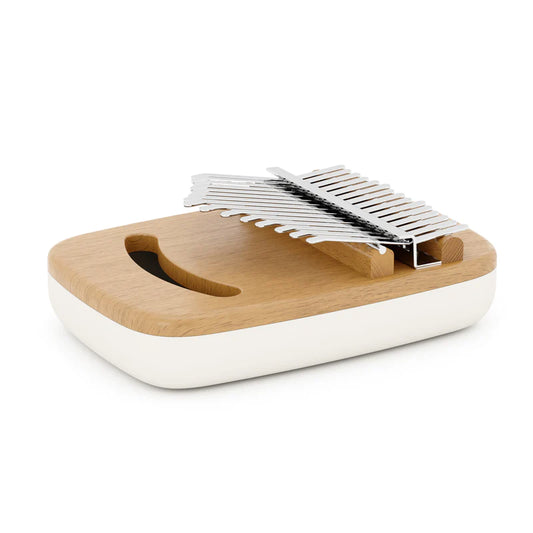 Instrumento musical UMBRA Strumba Kalimba, piano de polegares em madeira de faia natural, com teclas metálicas, base branca e design moderno de formas arredondadas.